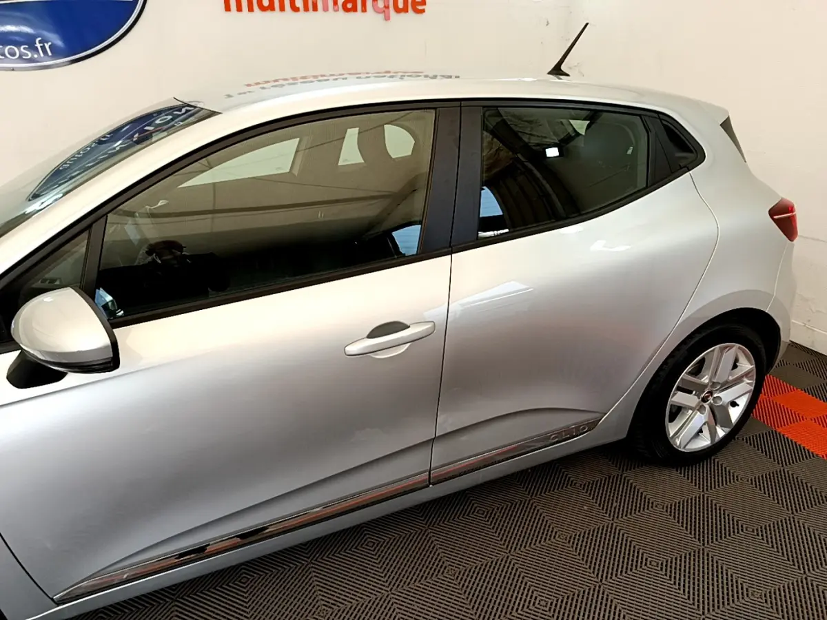 Profil droit d'une Renault Clio Business E-Tech hybride 2021 gris clair avec jantes alliage et poignées de porte intégrées.