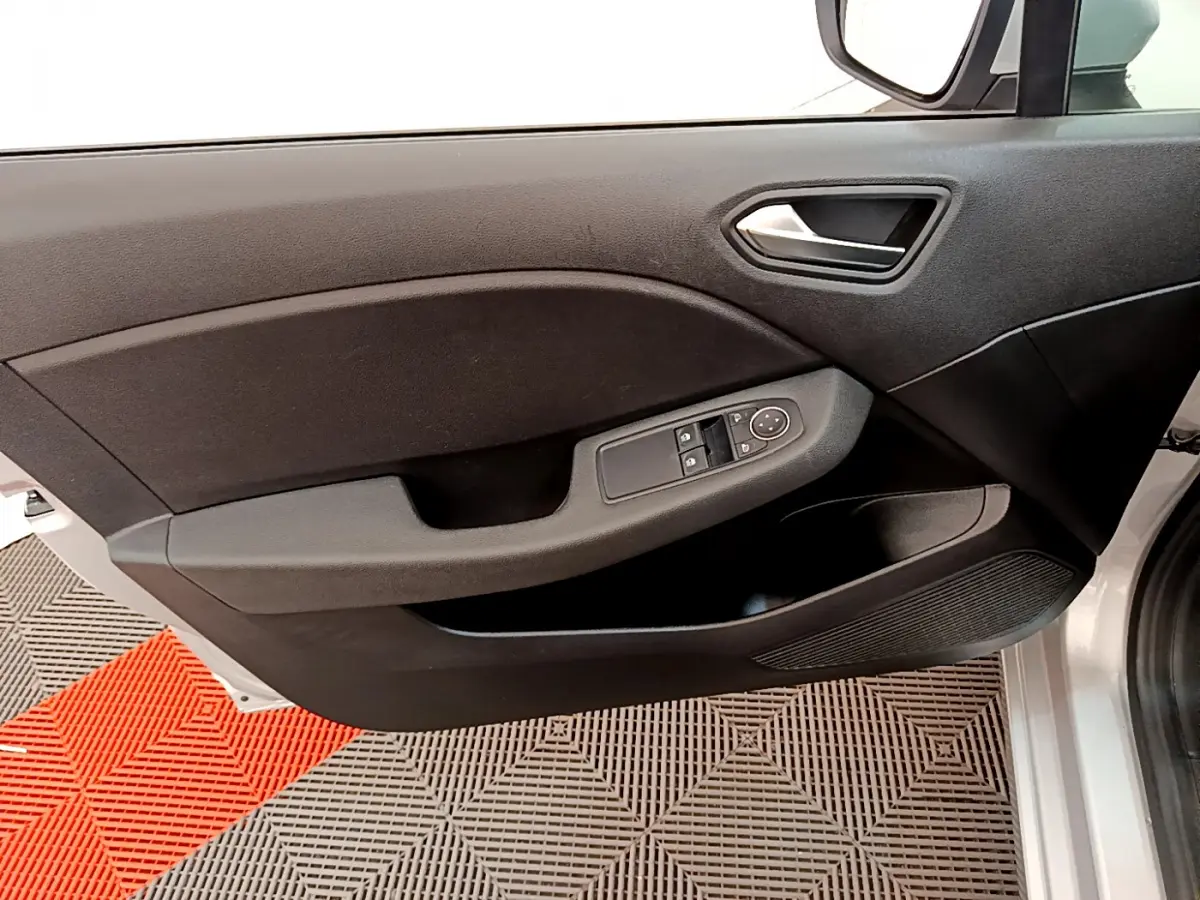Gros plan sur la porte avant gauche gris clair de la Renault Clio Business E-Tech hybride avec commandes électriques des vitres.