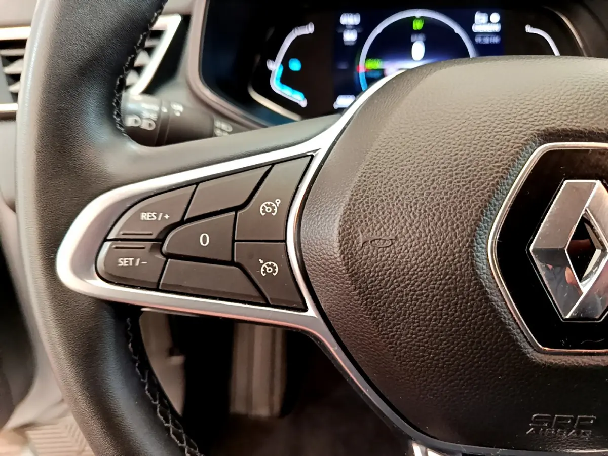 Gros plan sur le volant cuir noir de la Renault Clio Business E-Tech hybride 2021 avec commandes intégrées et logo central.