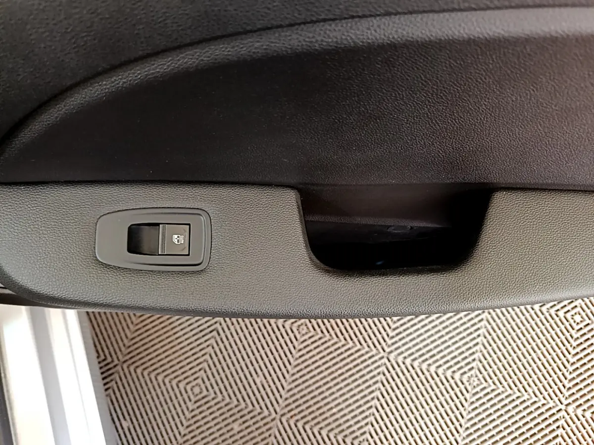 Gros plan sur la commande de verrouillage des portes intégrée à la garniture intérieure d'une Renault Clio gris clair.