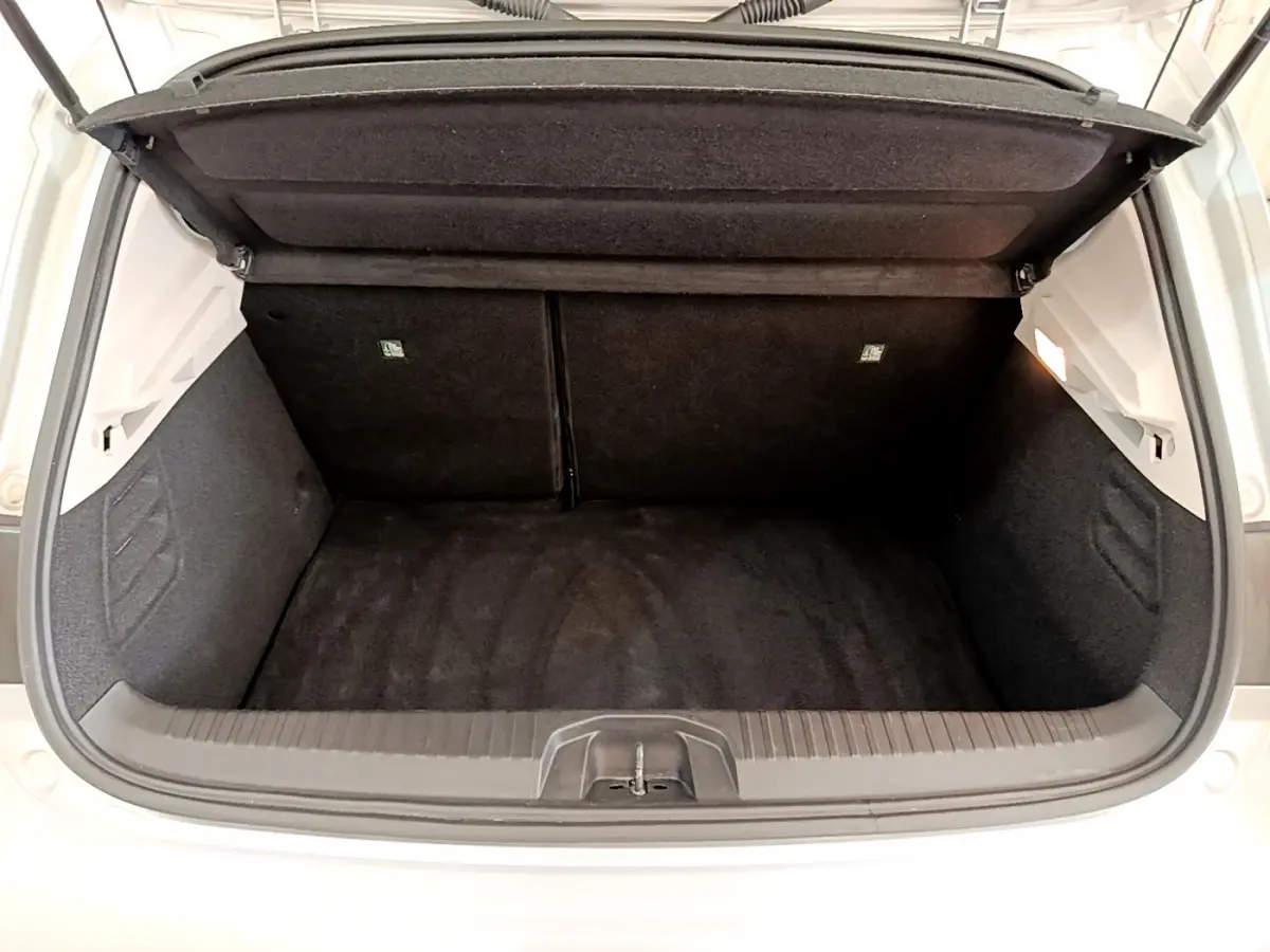 Coffre ouvert vu de l'arrière d'une Renault Clio Business E-Tech hybride gris clair, espace de chargement vide et tapis noir.