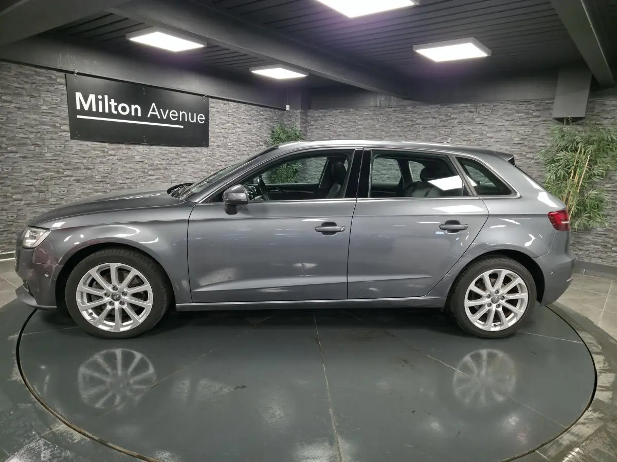 Audi A3 Sportback gris vue de profil côté gauche dans un showroom avec jantes aluminium 17 pouces.