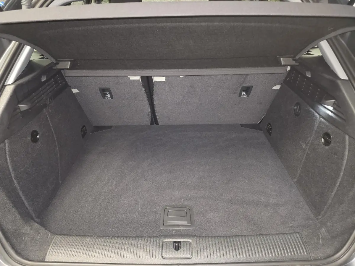 Coffre spacieux de l'Audi A3 Sportback gris, vue intérieure arrière avec tapis et banquette rabattable.