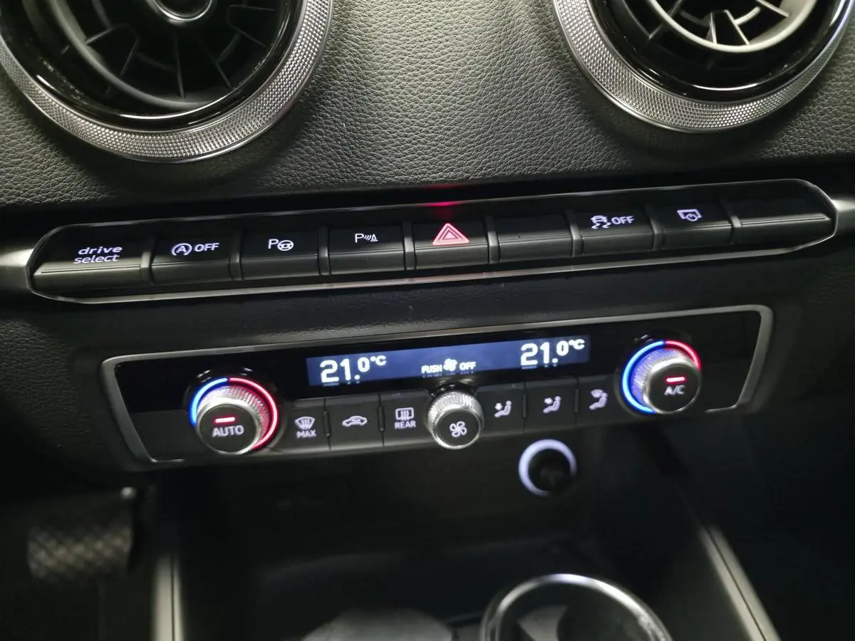 Gros plan sur la console centrale de l'Audi A3 Sportback gris, montrant la climatisation automatique bi-zone et les commandes.