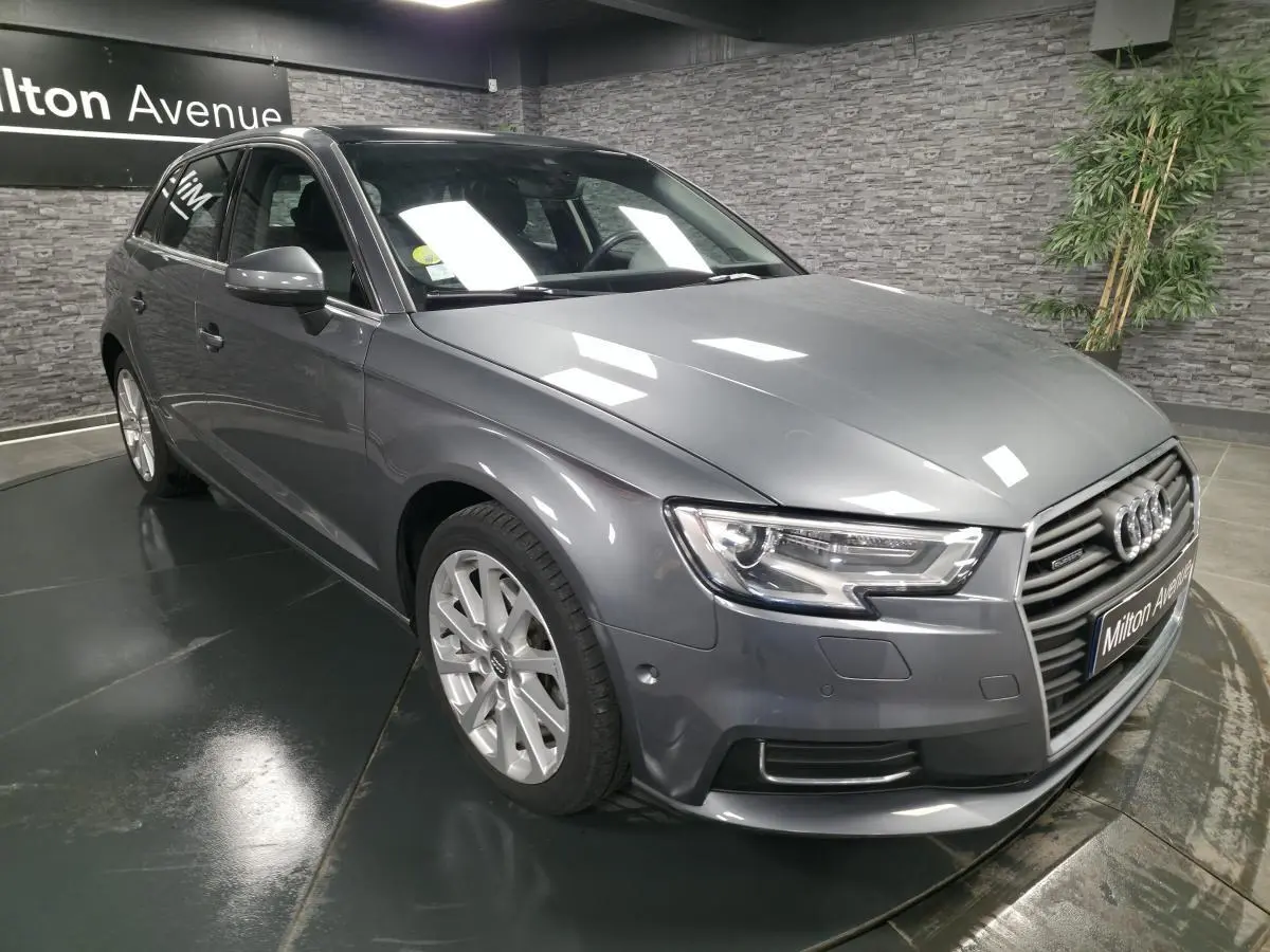 Audi A3 Sportback gris métallisé vue 3/4 avant droit dans un showroom avec éclairage intérieur.