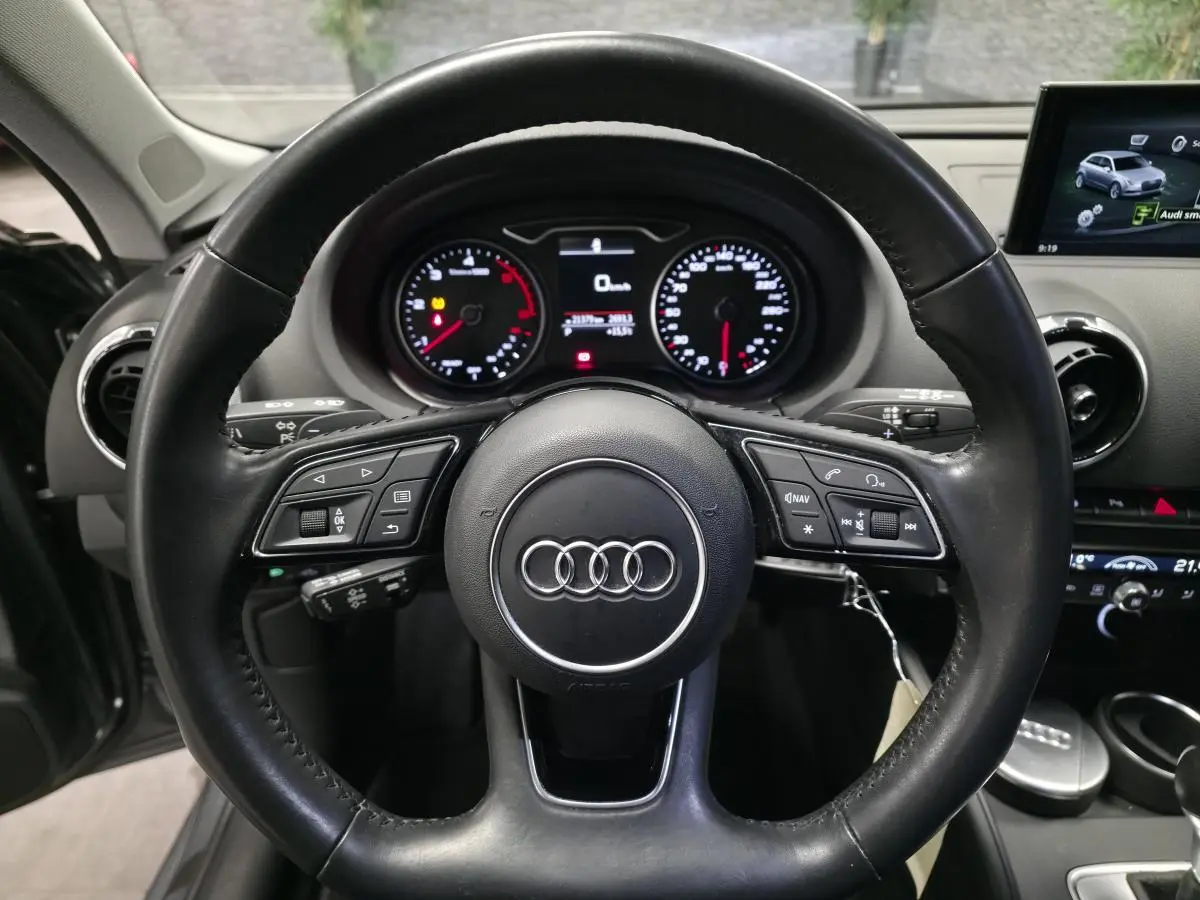 Vue intérieure centrée sur le volant cuir multifonction d'une Audi A3 Sportback 2017 avec tableau de bord et écran multimédia.