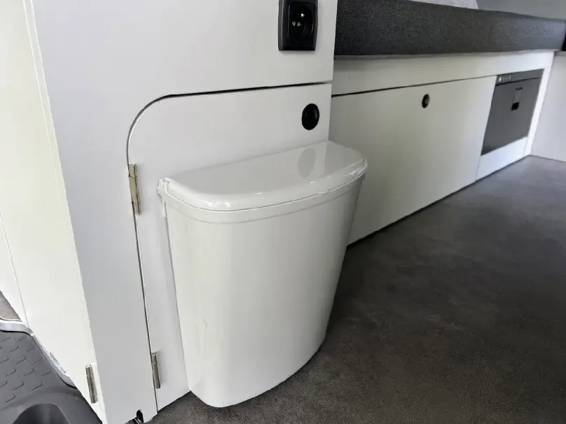 Détail intérieur montrant un petit bac blanc intégré au mobilier gris clair du fourgon aménagé Renault Trafic Fourgon gris.