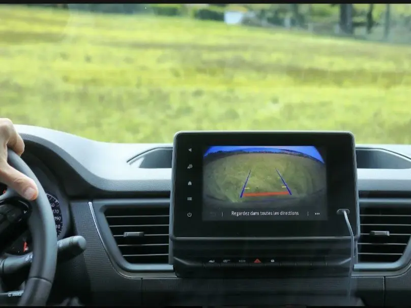 Vue intérieure du tableau de bord du Renault Trafic Fourgon 2025 avec écran de caméra de recul affichant l'arrière sur fond vert.