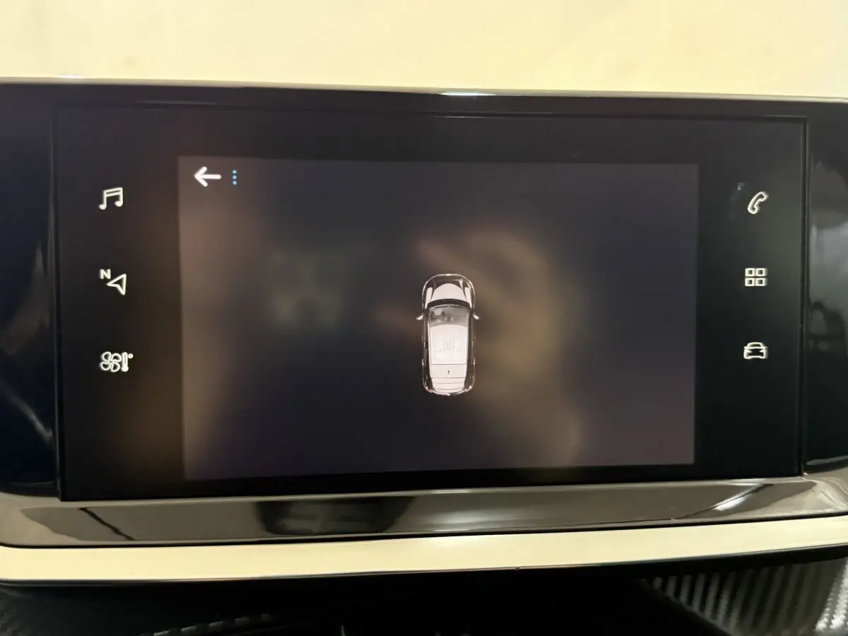 Écran tactile central affichant une vue aérienne de la Peugeot 208 blanche, intérieur moderne et épuré.