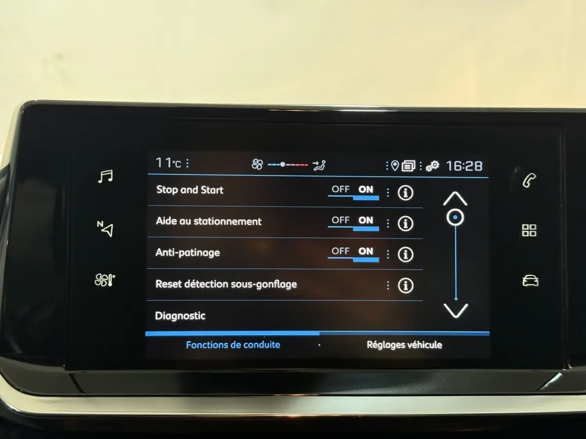 Écran tactile central de la Peugeot 208 blanc montrant les réglages d’aide à la conduite et d’anti-patinage.