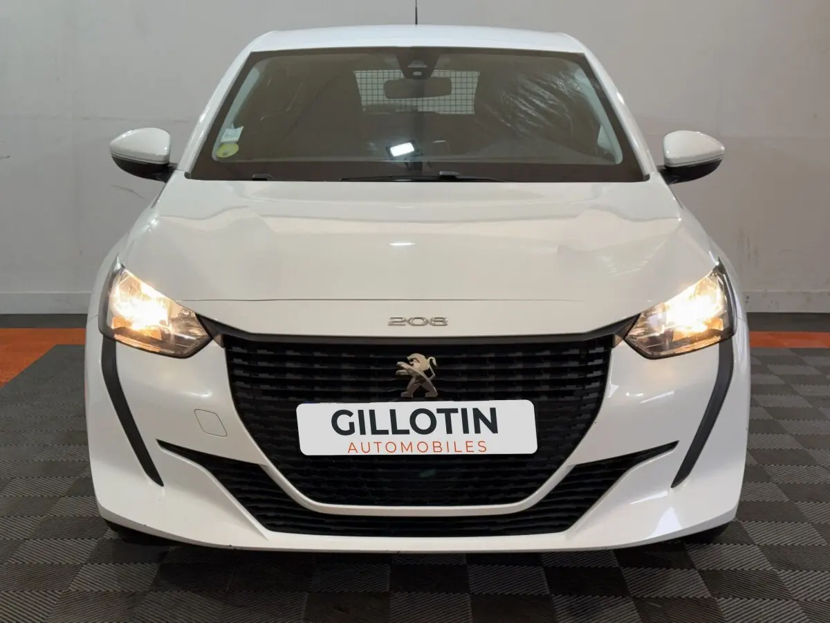 Vue frontale d'une Peugeot 208 blanche de 2021 avec phares allumés et calandre noire distinctive.