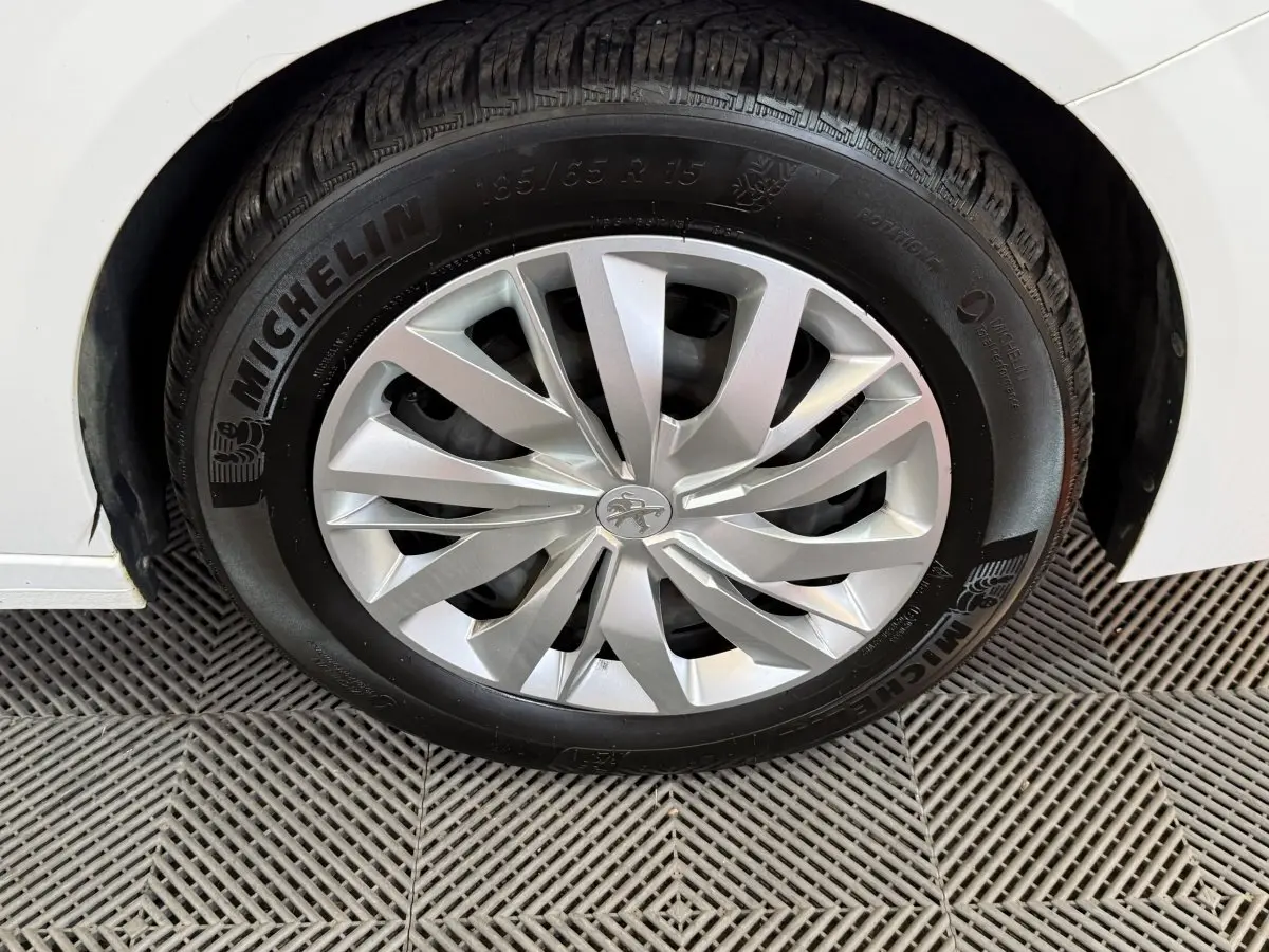 Gros plan sur la roue avant droite blanche d'une Peugeot 208 1.5 BlueHDi avec jante alu et pneu Michelin.