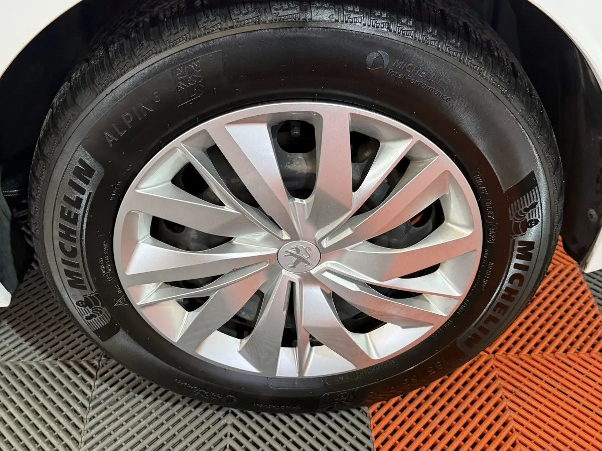 Gros plan sur la roue avant droite blanche d'une Peugeot 208 1.5 BlueHDi avec jante argentée et pneu Michelin.