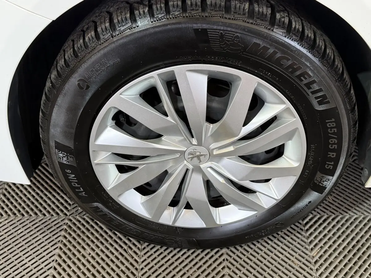 Gros plan sur la roue avant droite blanche d'une Peugeot 208 1.5 BlueHDi avec jante argentée et pneu Michelin.