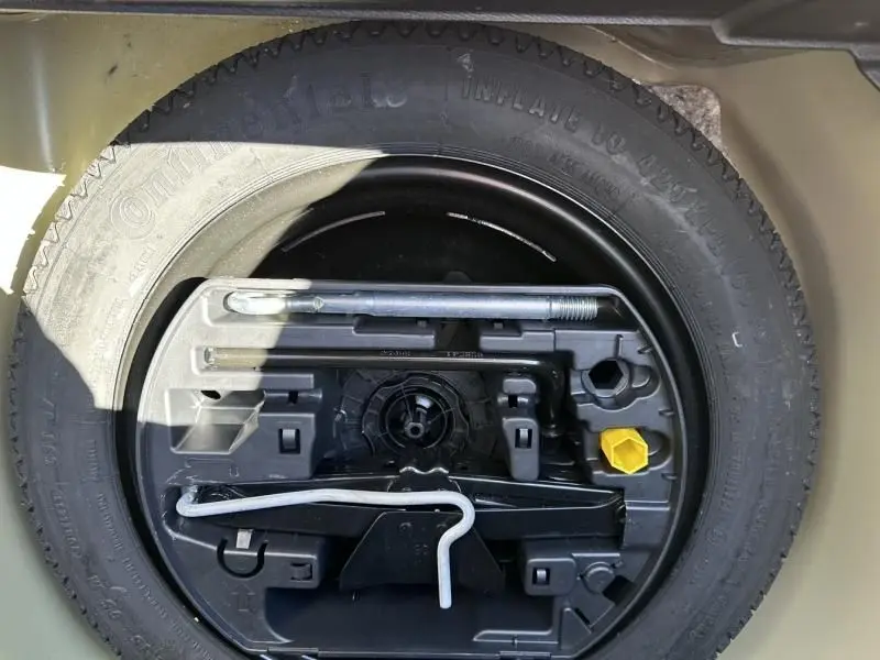 Gros plan sur la roue de secours et les outils de bord du coffre d'une Peugeot 208 jaune faro 2020.