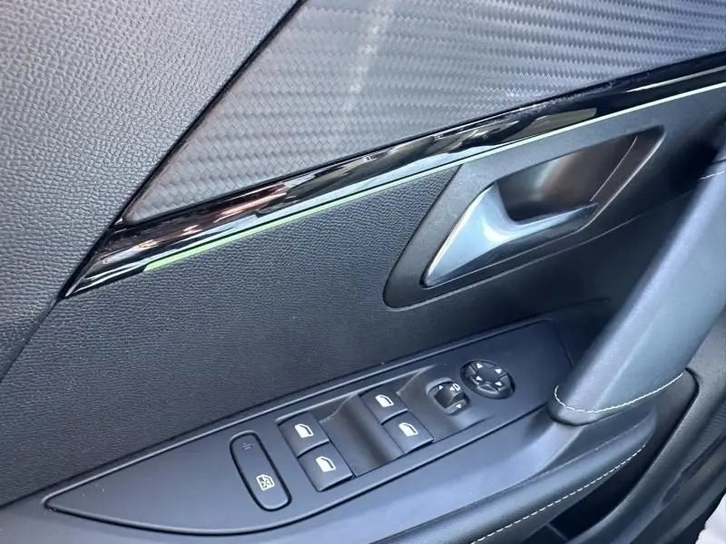 Détail intérieur côté gauche de la porte d’une Peugeot 208 GT Line 2020, avec commandes de vitres et garniture noire.