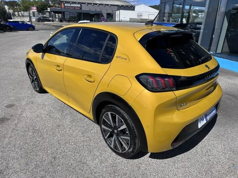 Vue 3/4 arrière droite d'une Peugeot 208 GT Line jaune faro avec jantes alliage et vitres teintées.