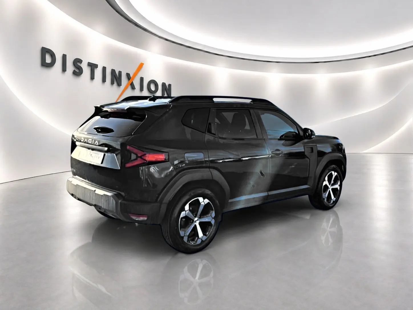 Vue 3/4 arrière droite d'un Dacia Duster noir 2026 avec jantes alu et barres de toit dans un showroom lumineux.