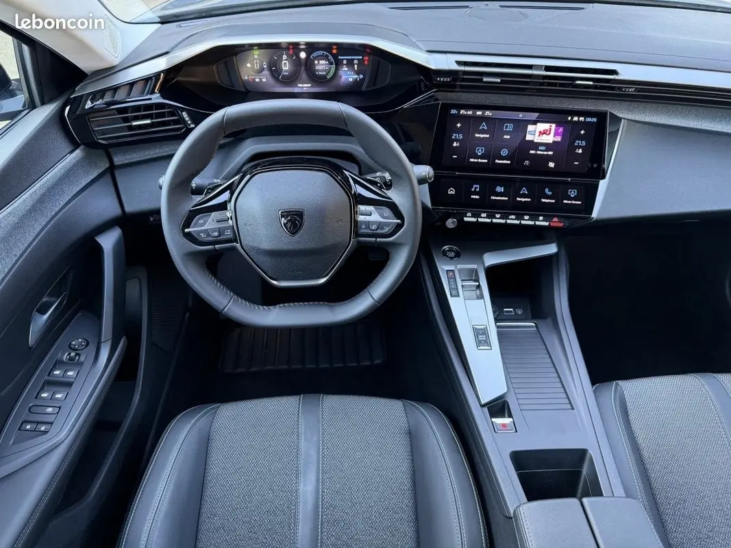 Vue intérieure centrée sur le volant cuir et tableau de bord numérique de la Peugeot 308 Hybrid 145 e-DCS6 Allure 2025.