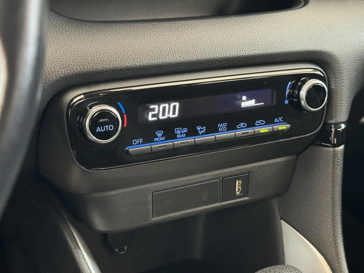 Gros plan sur la console centrale noire de la Toyota Yaris hybride 2022 avec affichage digital de la climatisation à 20°C.
