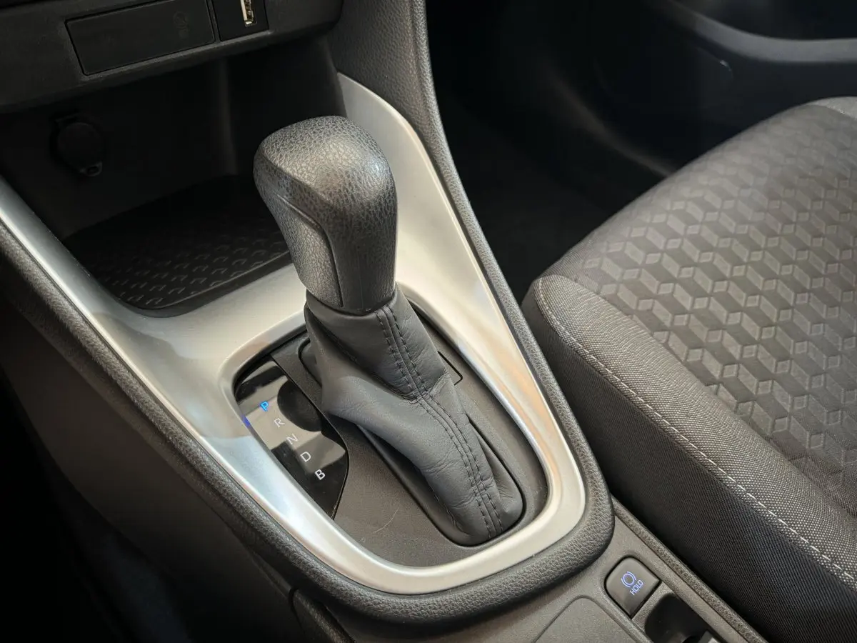 Le levier de boîte automatique noir de la Toyota Yaris hybride 2022 vu en gros plan côté droit avec siège tissu gris.