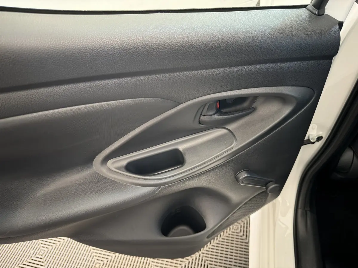 Gros plan sur la porte avant gauche noire intérieure d'une Toyota Yaris blanche hybride 2022 avec poignée et manivelle de vitre.