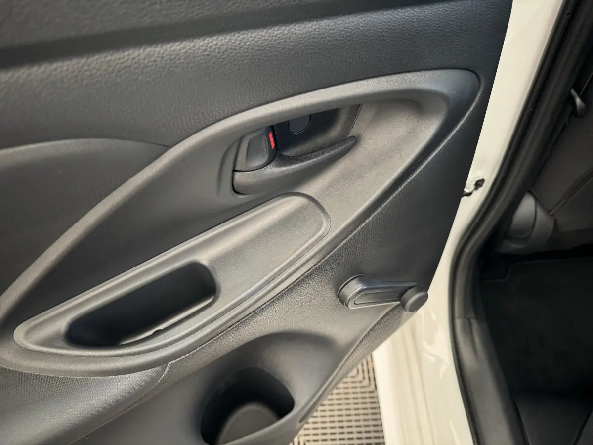 Gros plan sur la porte arrière droite blanche d'une Toyota Yaris Hybride 116h, avec poignée intérieure et manivelle de vitre.