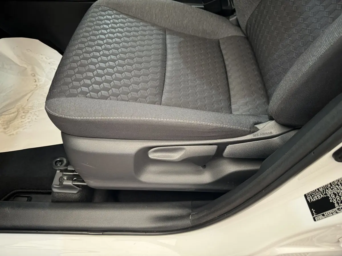 Gros plan sur le siège avant droit gris foncé de la Toyota Yaris hybride blanche, avec réglage manuel visible.