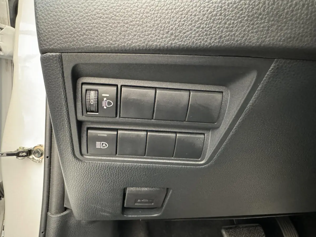 Panneau de commandes côté conducteur de Toyota Yaris blanche 2022, avec réglage phares et bouton auto start-stop.
