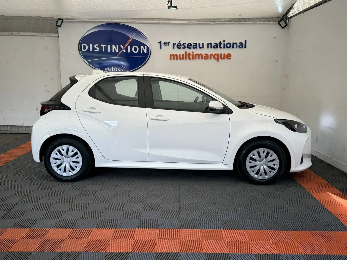 Profil côté droit d'une Toyota Yaris blanche 2022 hybride, avec jantes standard et toit noir contrastant.