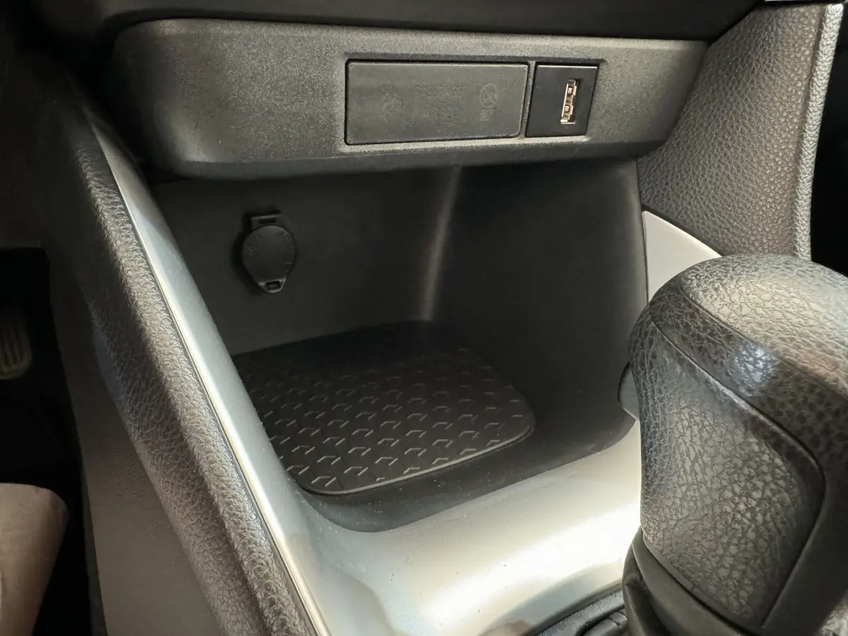 Gros plan sur la console centrale noire de la Toyota Yaris hybride 2022, avec prise USB et levier de boîte automatique.