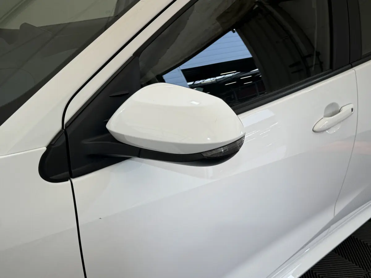 Rétroviseur côté gauche blanc de la Toyota Yaris hybride 2022, avec poignée de porte assortie visible en arrière-plan.