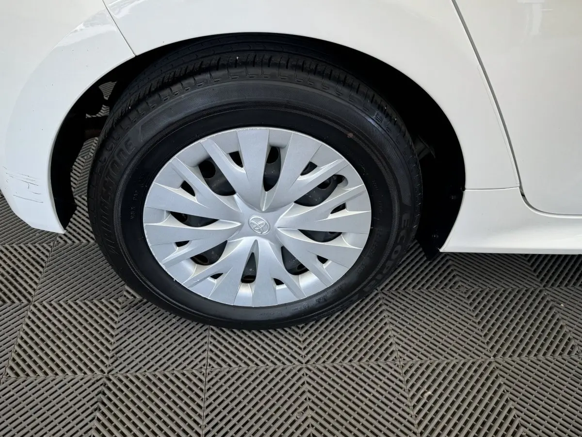 Gros plan sur la roue avant droite blanche d'une Toyota Yaris hybride 2022 avec enjoliveur argenté au design épuré.