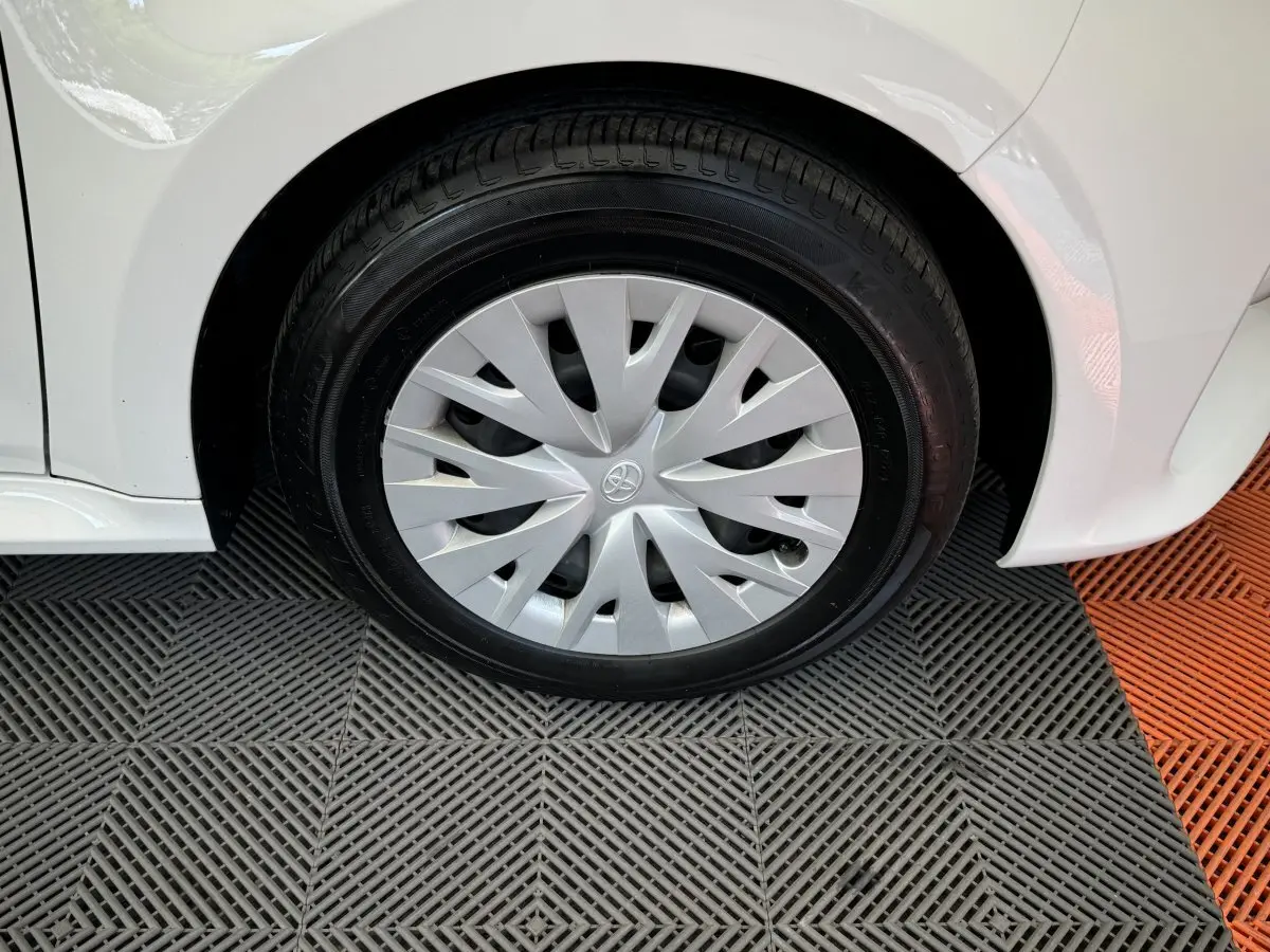 Gros plan sur la roue avant droite d'une Toyota Yaris blanche 2022 avec enjoliveur argenté au design en spirale.