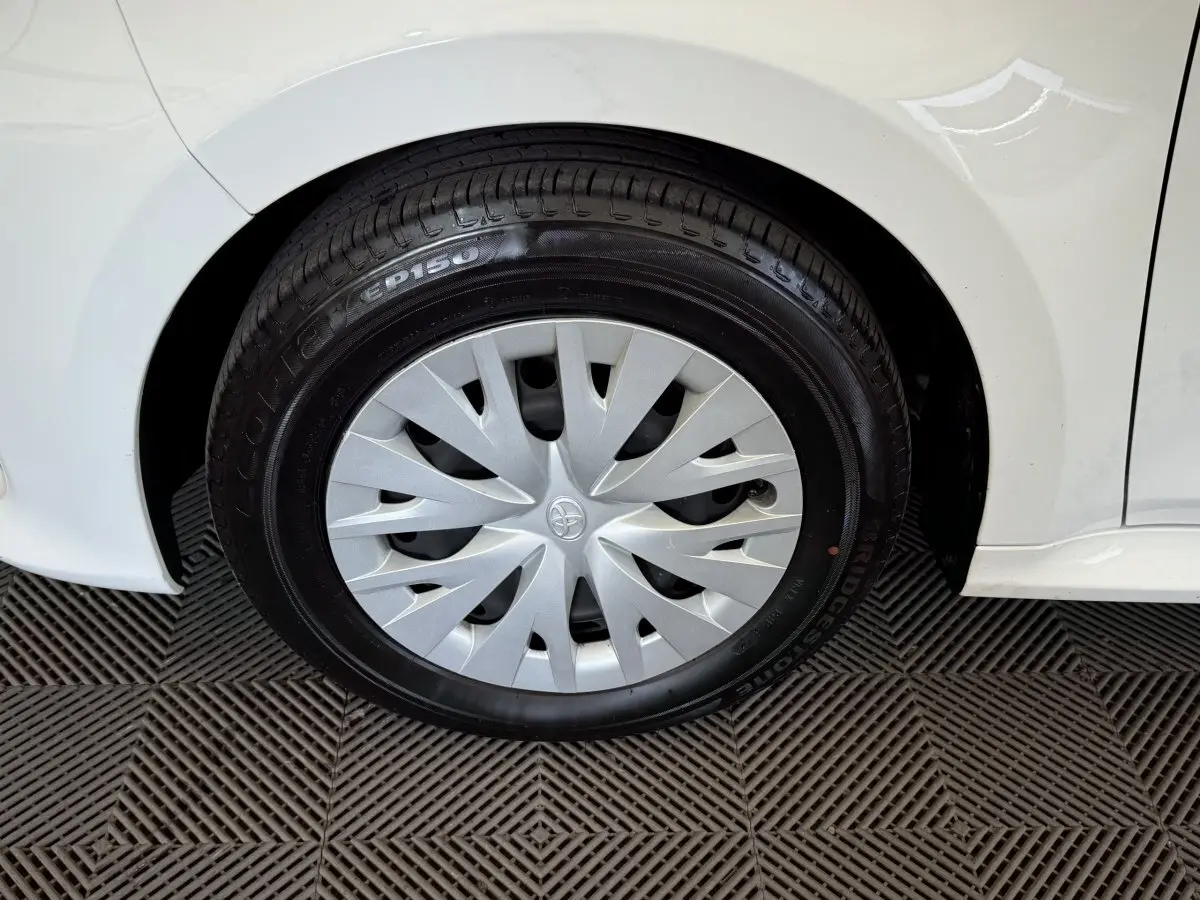 Gros plan sur la roue arrière droite blanche d'une Toyota Yaris hybride 2022 avec enjoliveur argenté au design en spirale.