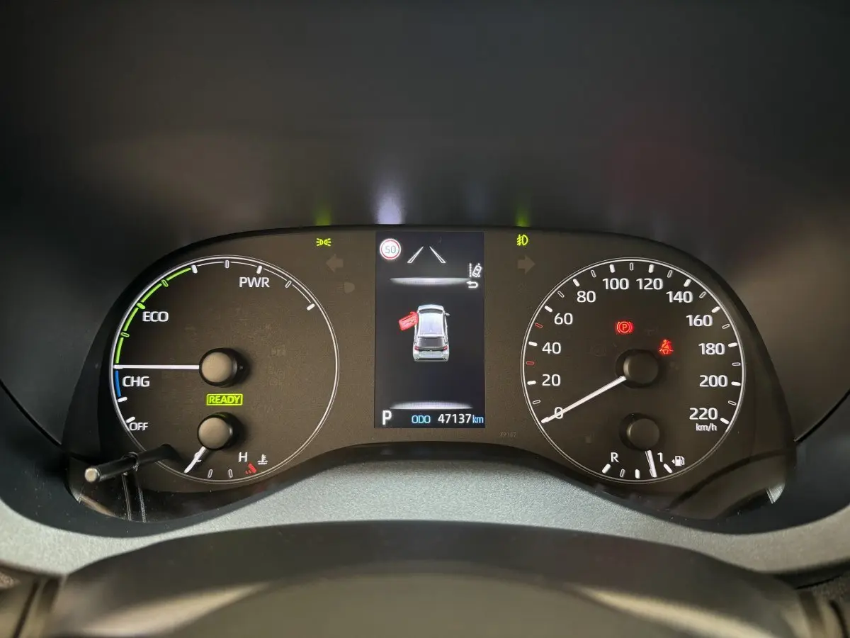 Tableau de bord de Toyota Yaris hybride 2022 montrant compte-tours, vitesse, et écran central avec alertes et kilométrage.