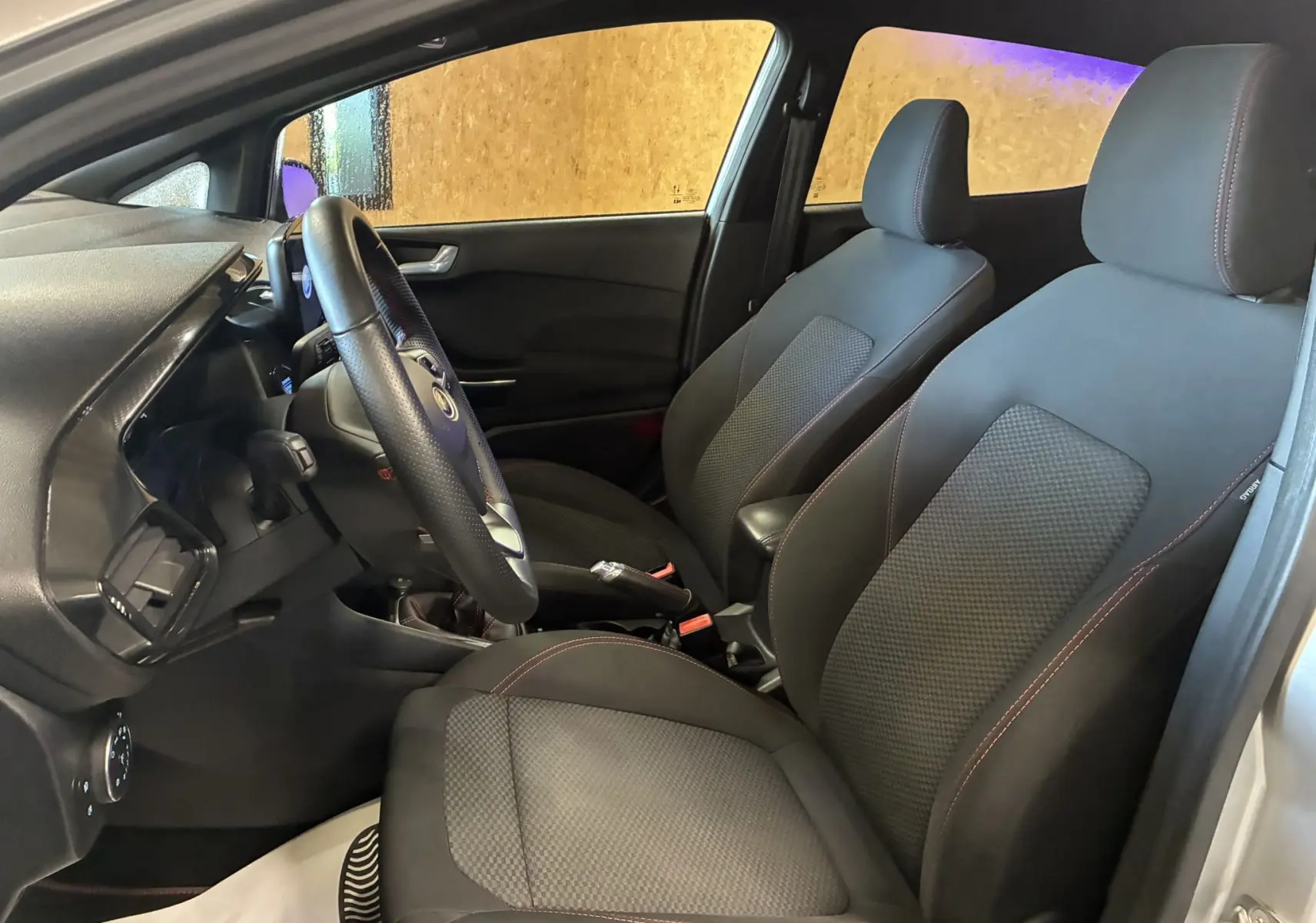 Vue intérieure côté conducteur de la Ford Fiesta 1.0 EcoBoost 95 ST Line 2020 avec sièges tissu gris et volant multifonction.