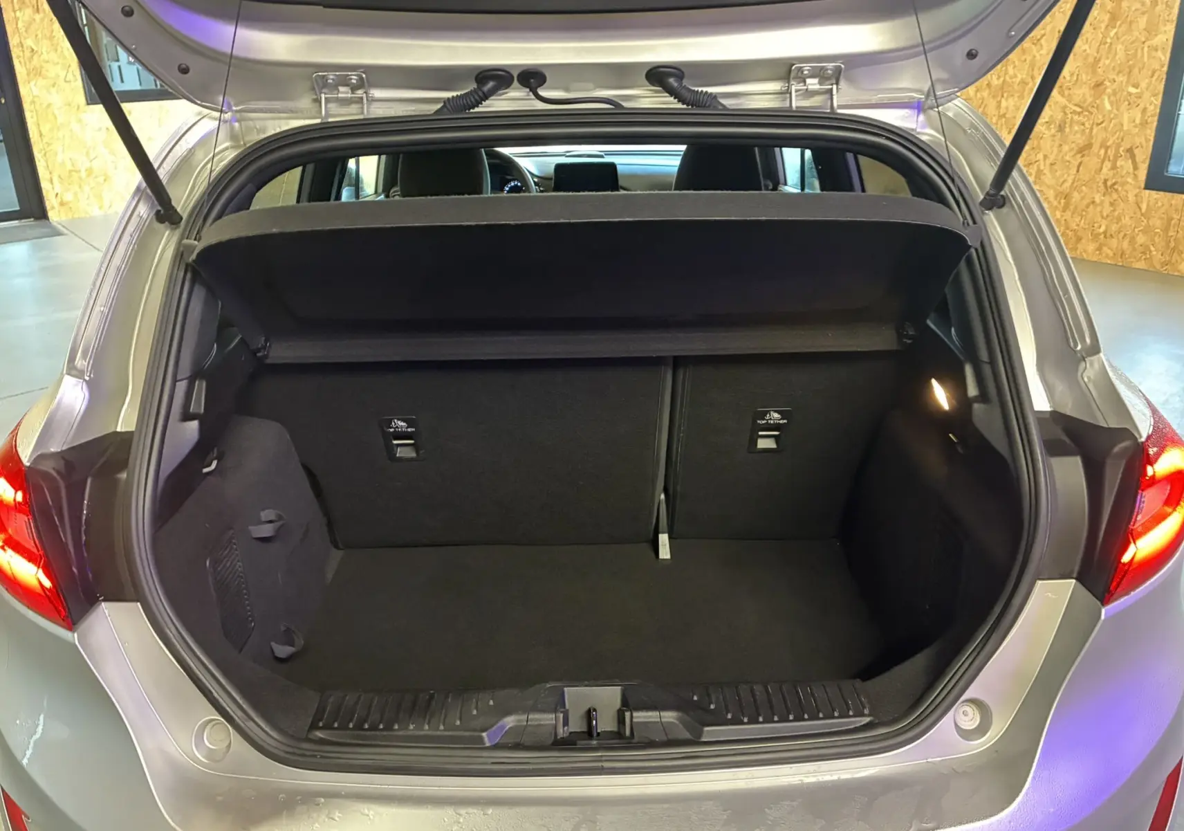 Coffre ouvert vu de l'arrière d'une Ford Fiesta gris 2020, montrant l'espace de chargement et la plage arrière relevée.