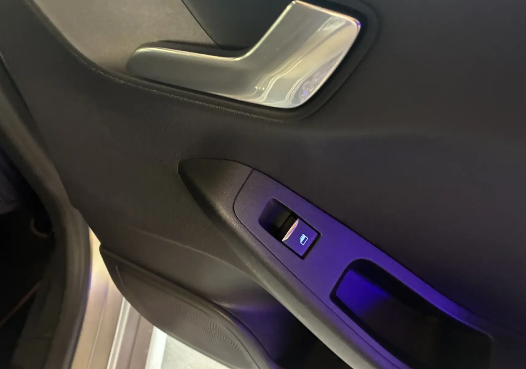 Gros plan sur la commande de lève-vitre côté gauche de la porte intérieure noire d'une Ford Fiesta gris 2020.