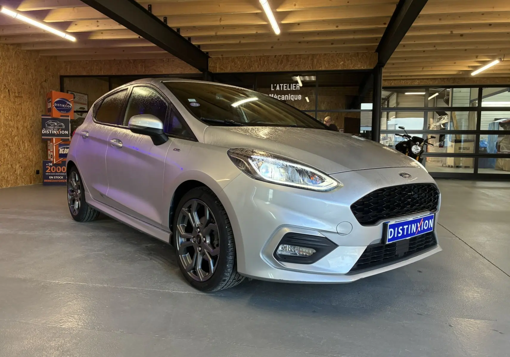 Ford Fiesta 1.0 EcoBoost gris vue 3/4 avant droit dans un garage avec jantes alliage foncé et calandre noire.