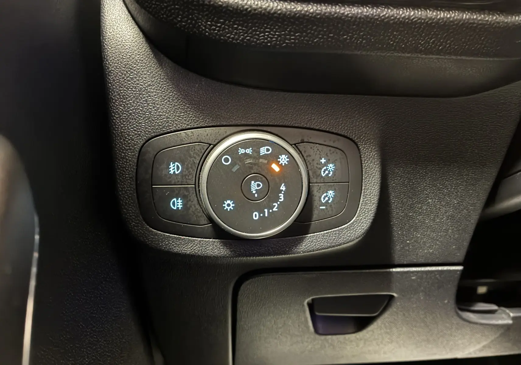Gros plan sur le bouton de réglage des phares du tableau de bord noir de la Ford Fiesta gris 2020.