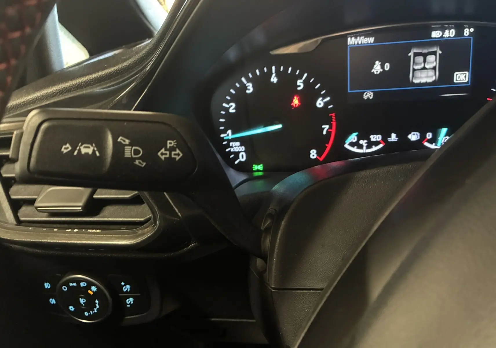 Gros plan sur le tableau de bord et levier de clignotant d'une Ford Fiesta gris 2020, affichage digital et compte-tours visibles.