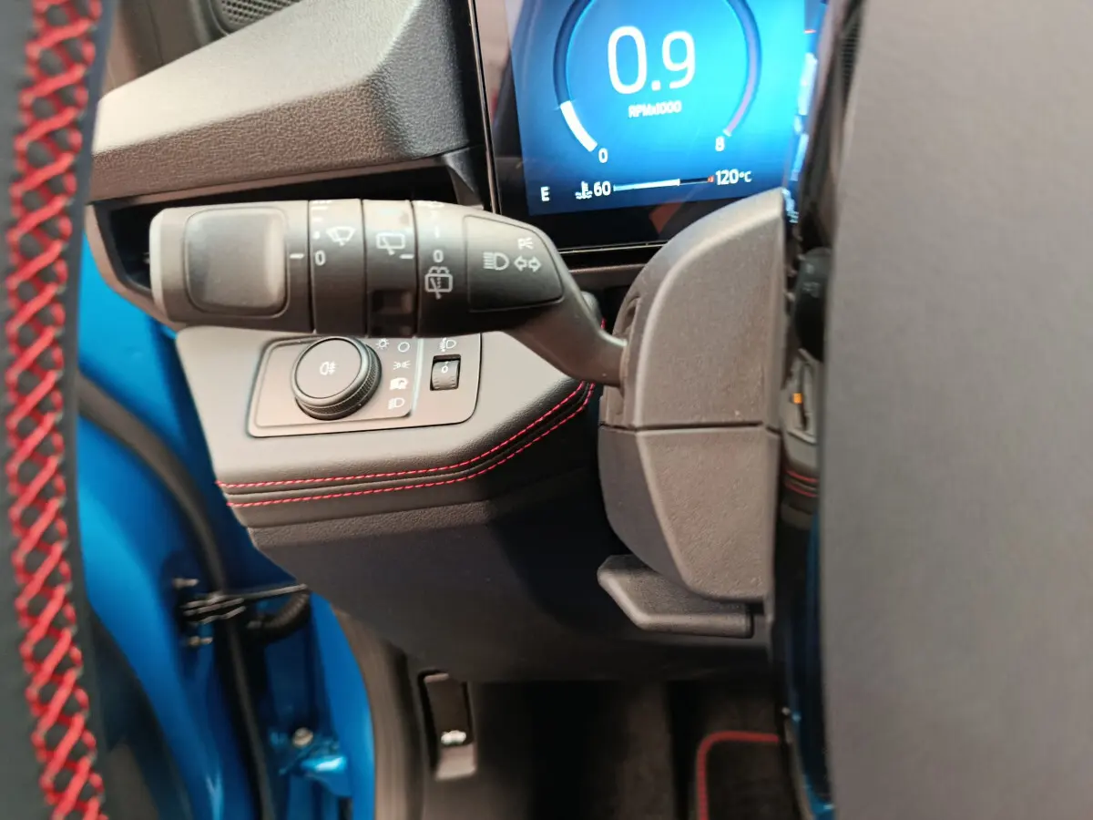 Gros plan sur la commande des phares et clignotants du Ford Puma bleu, avec tableau de bord digital lumineux en arrière-plan.