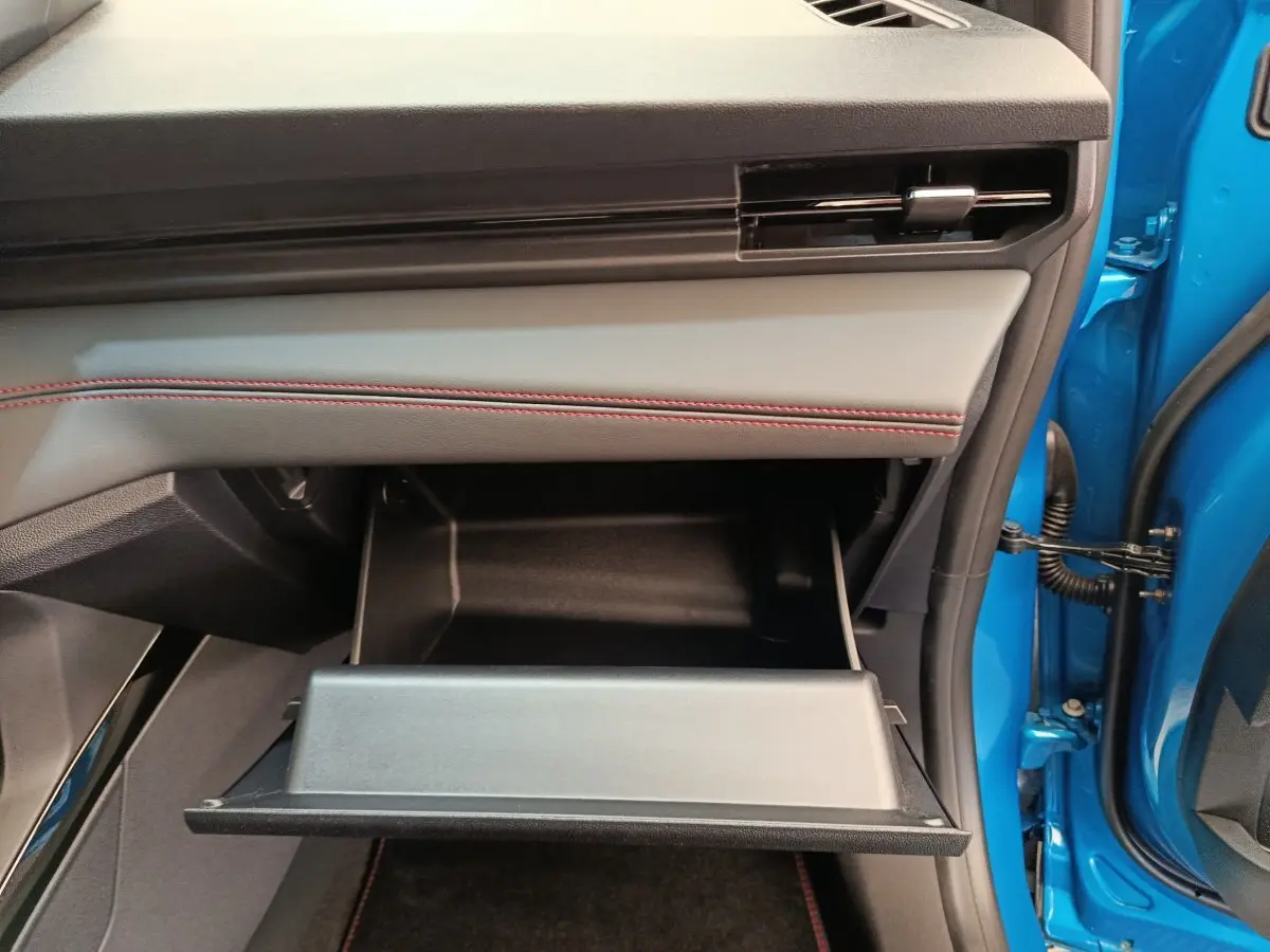 Gros plan sur la boîte à gants ouverte côté passager du Ford Puma bleu, soulignant la finition intérieure avec surpiqûres rouges.