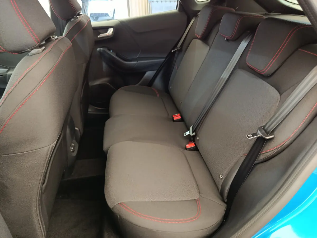 Vue intérieure côté droit sur la banquette arrière noire avec surpiqûres rouges du Ford Puma bleu 2025 ST-LINE.