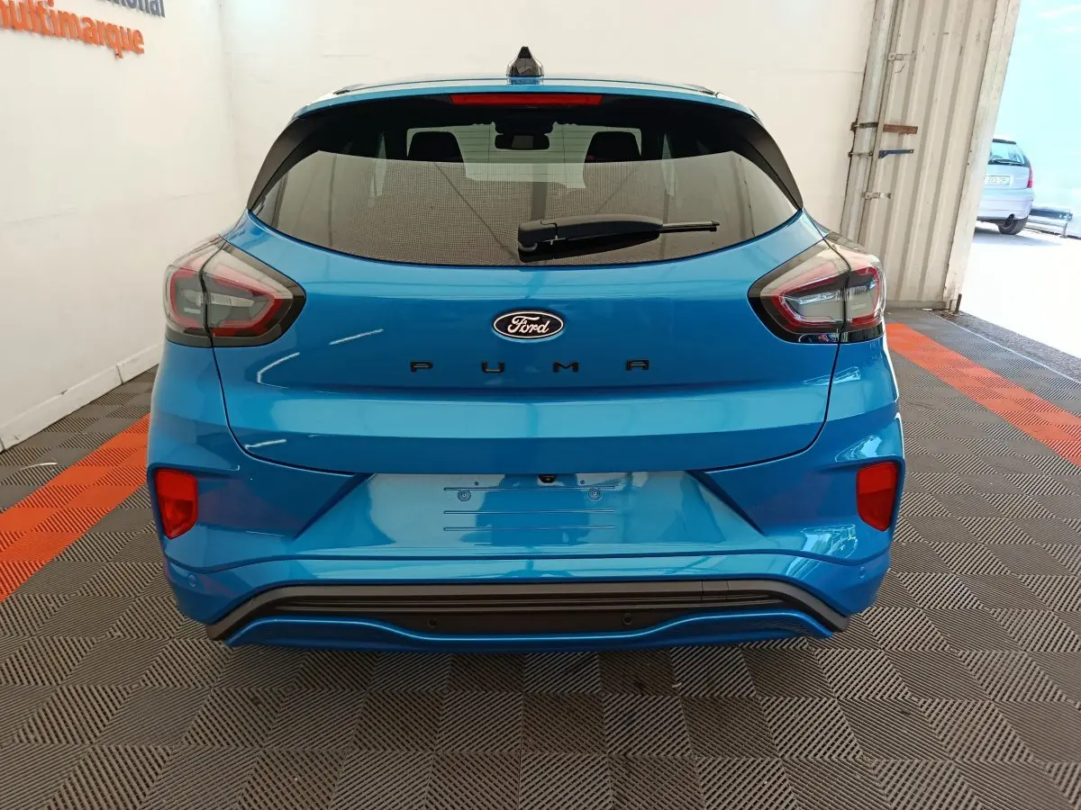 Vue arrière d'un Ford Puma bleu 2025 avec feux LED et logo Ford bien visibles sur un sol à damiers.