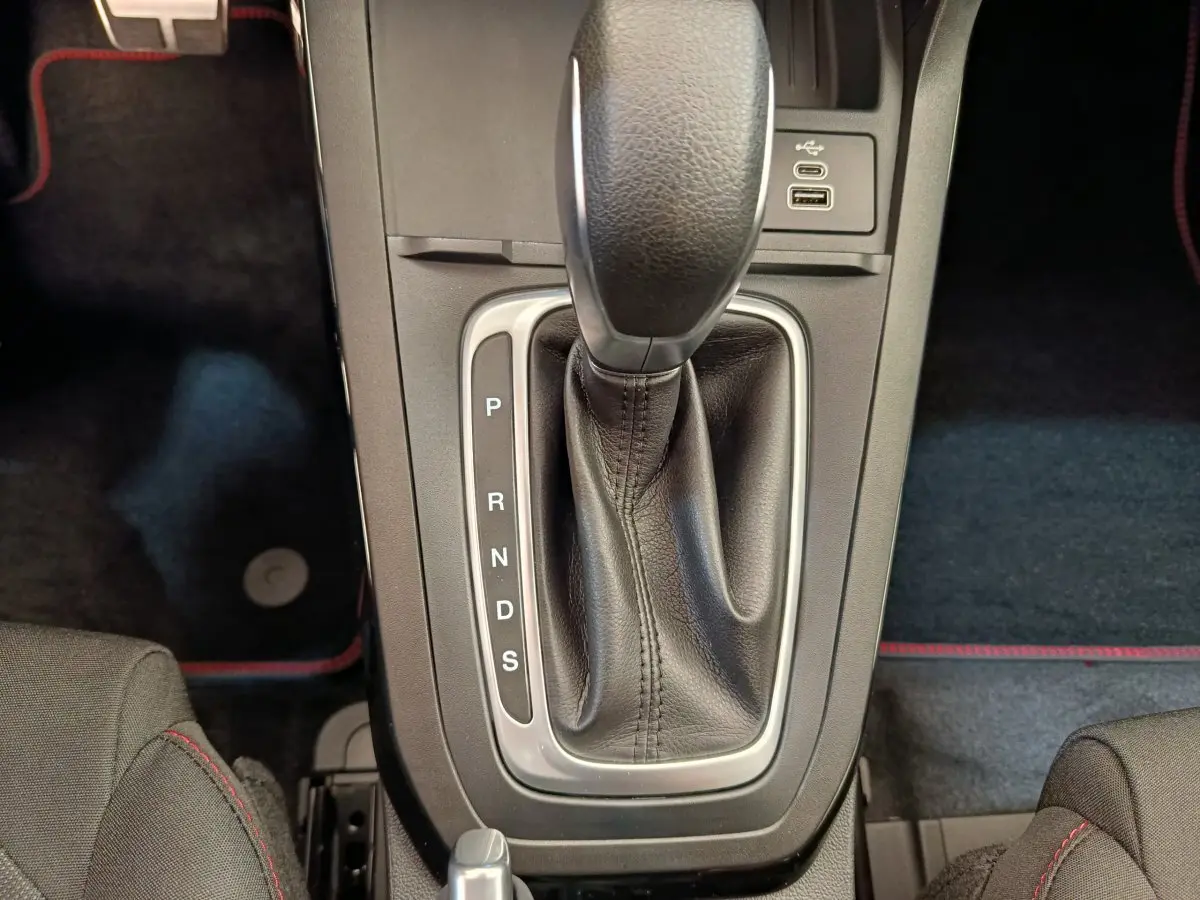 Le levier de boîte automatique noir du Ford Puma 2025 vu de dessus avec coutures rouges sur les sièges adjacents.