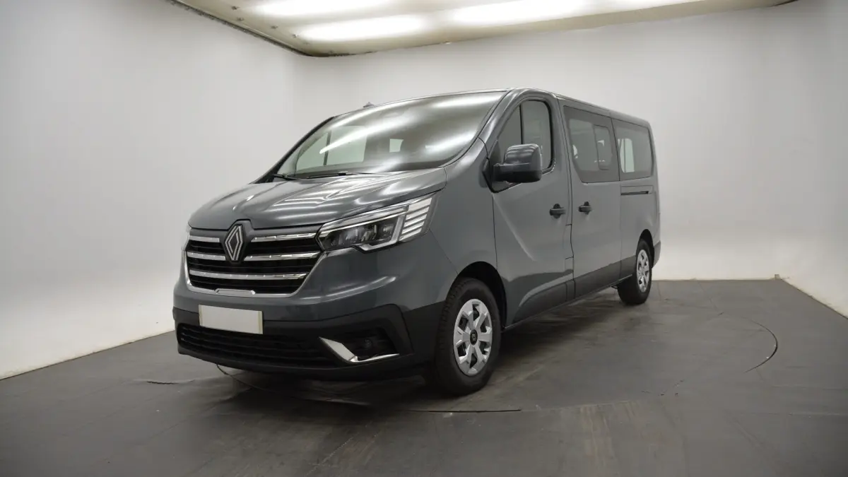 Renault Trafic Fourgon gris clair vu en 3/4 avant droit, avec calandre chromée et feux LED distinctifs.