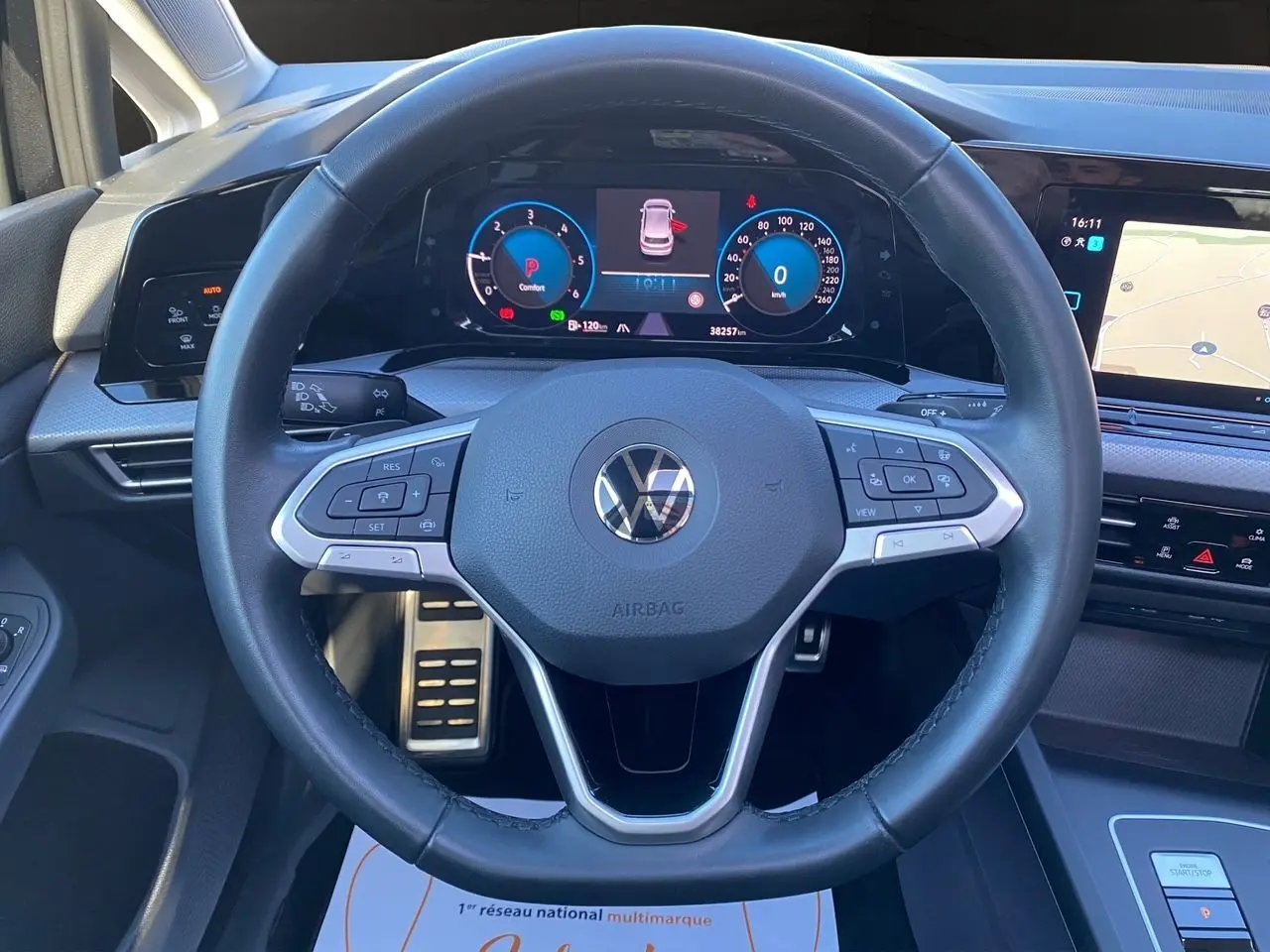 Vue centrée sur le volant cuir multifonction noir de la Volkswagen Golf VIII avec tableau de bord digital et écran tactile.