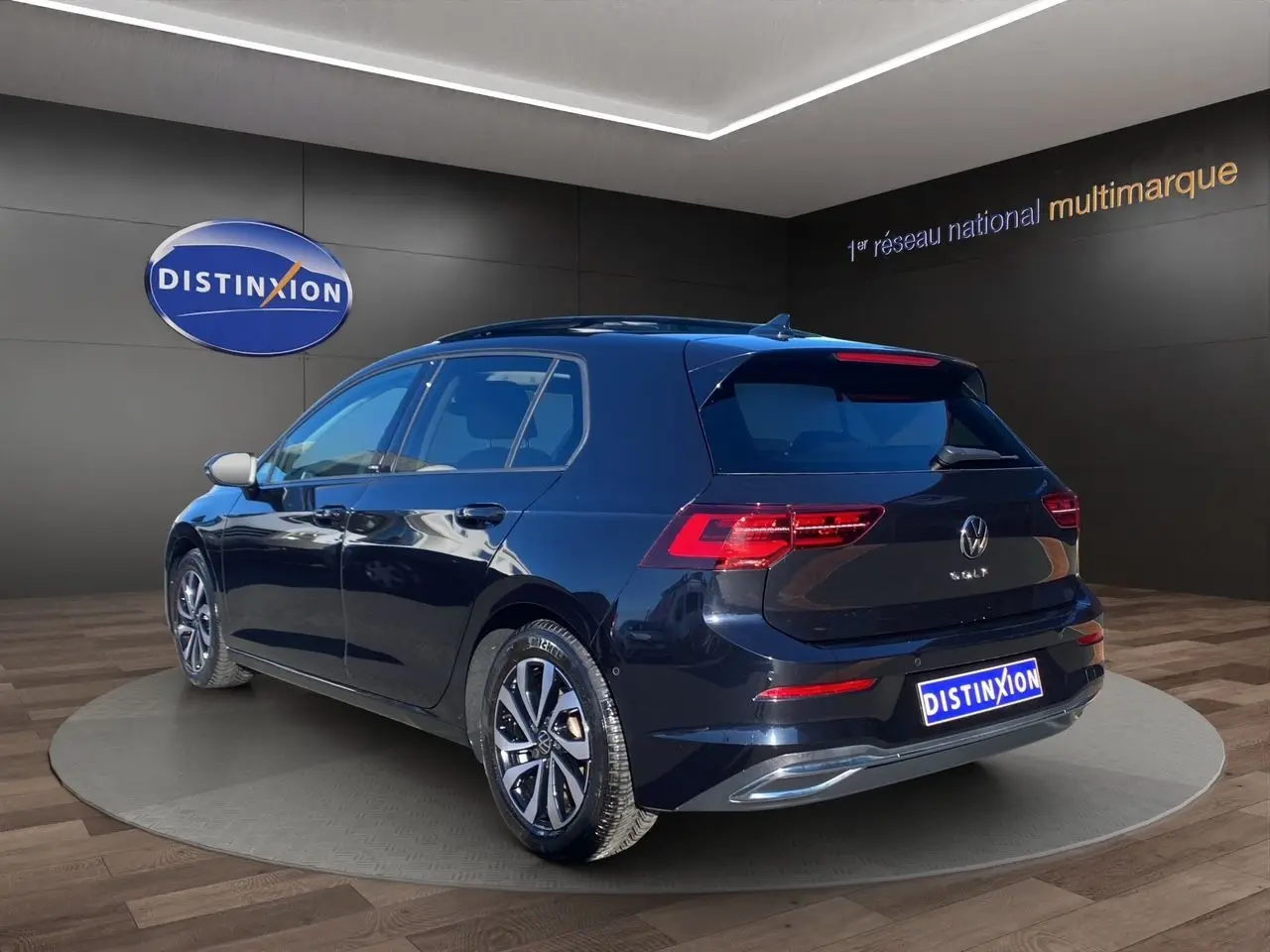 Vue 3/4 arrière droite d'une Volkswagen Golf VIII noire avec toit panoramique et jantes alu 16 pouces.